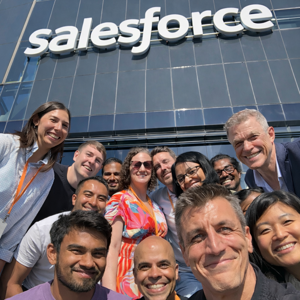 Group of smiling people in front of a salesforce building.